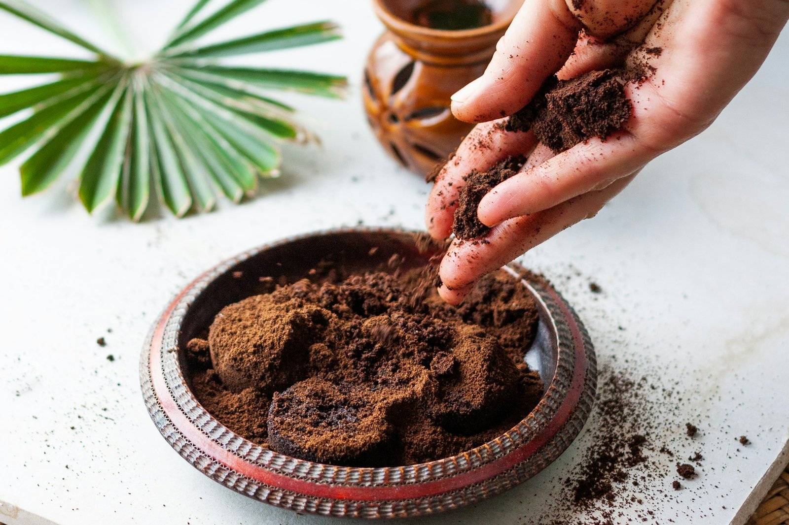 woman's hand crumbles coffee grounds into wooden bowl. Len blázon by vyhodil kávovú usadeninu. Takto ju doma využijete